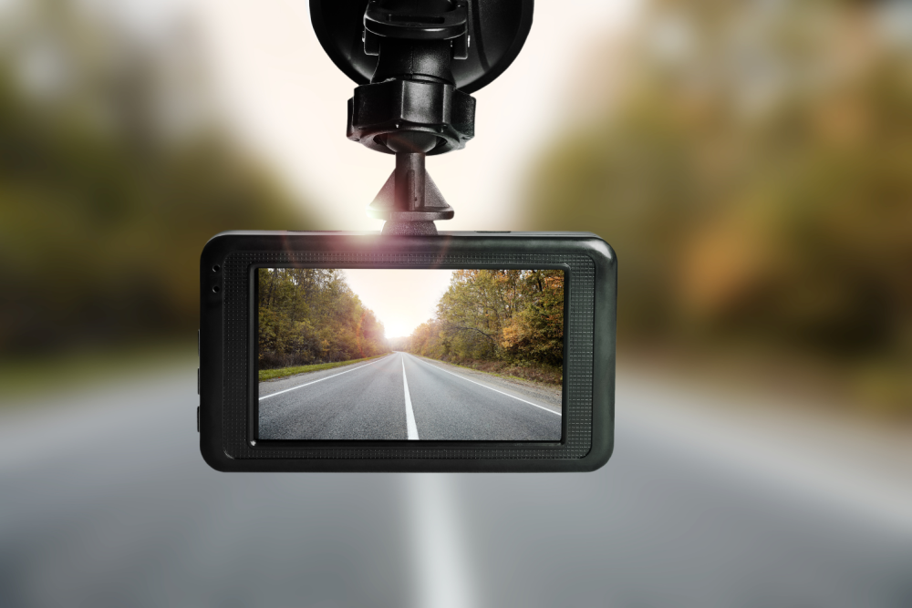 Close-up of a dashboard camera recording a road view through a car windshield.