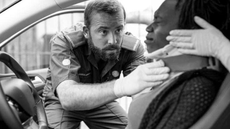 Paramedic assists car accident victim with neck brace for safety and care.