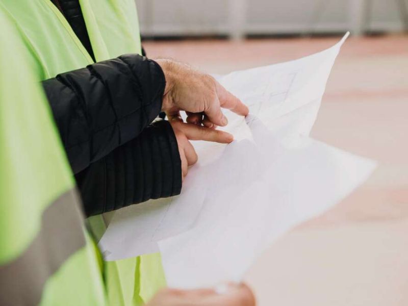 Construction workers reviewing blueprints on site.