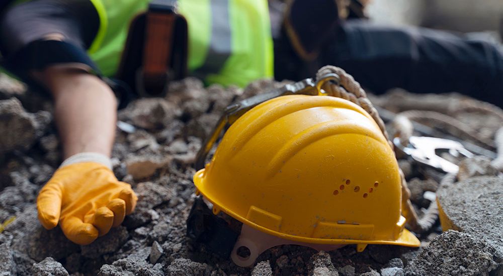 Construction accident scene with fallen worker, hard hat, and rubble, highlighting workplace safety concerns.