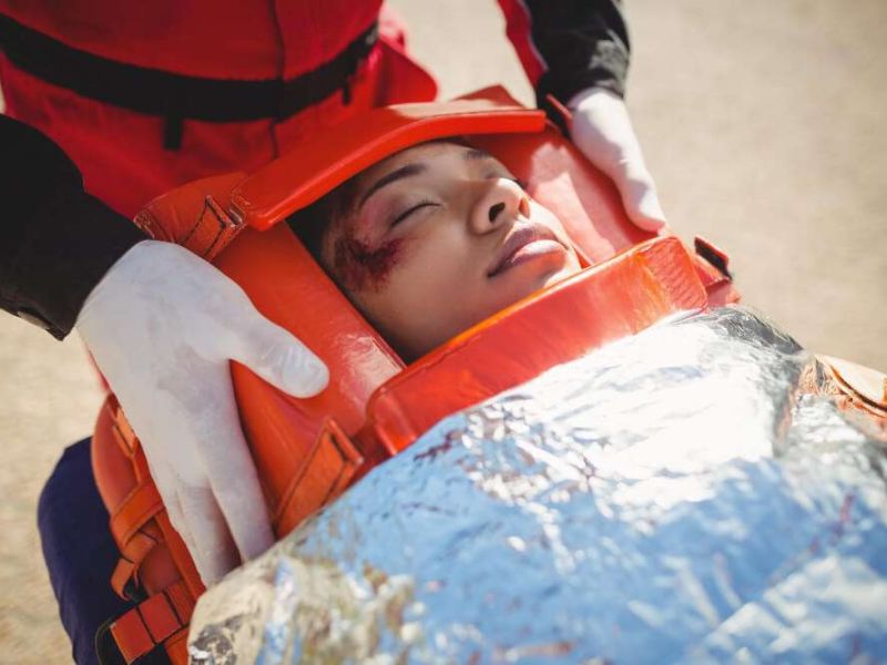 Rescue worker assisting injured person with head brace, emergency care concept.