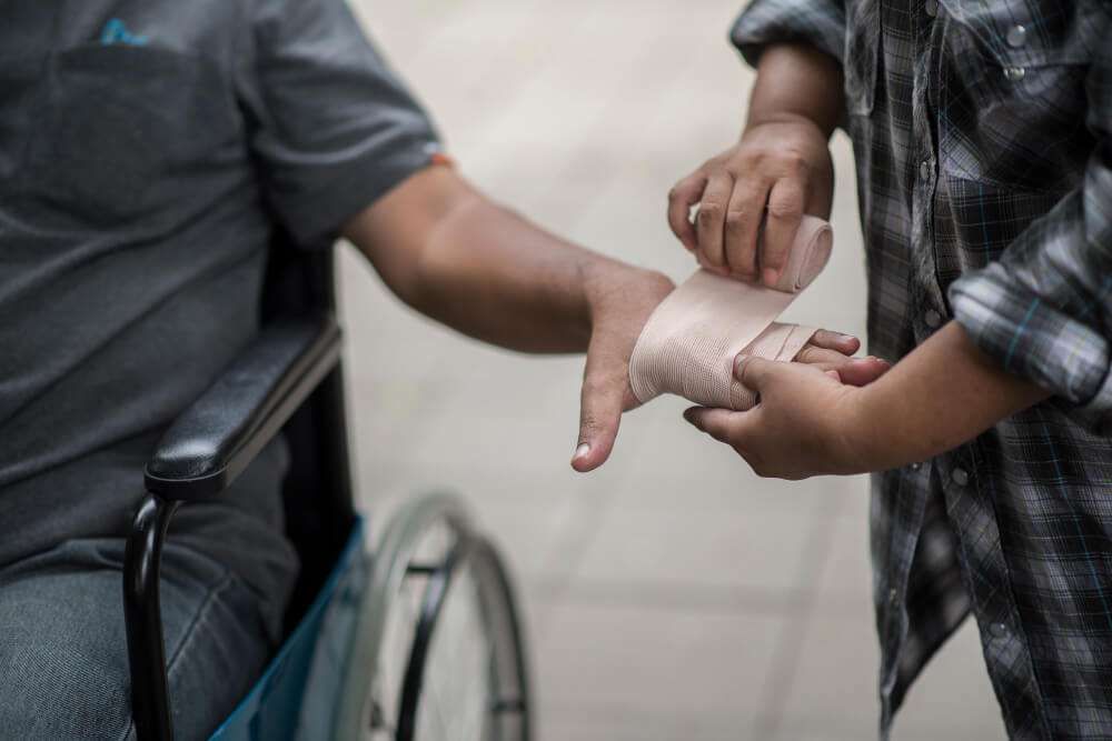 Person in wheelchair receiving arm bandage.