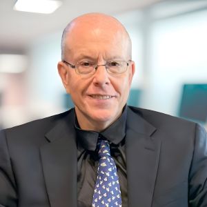 Business professional in a suit smiling in office setting.