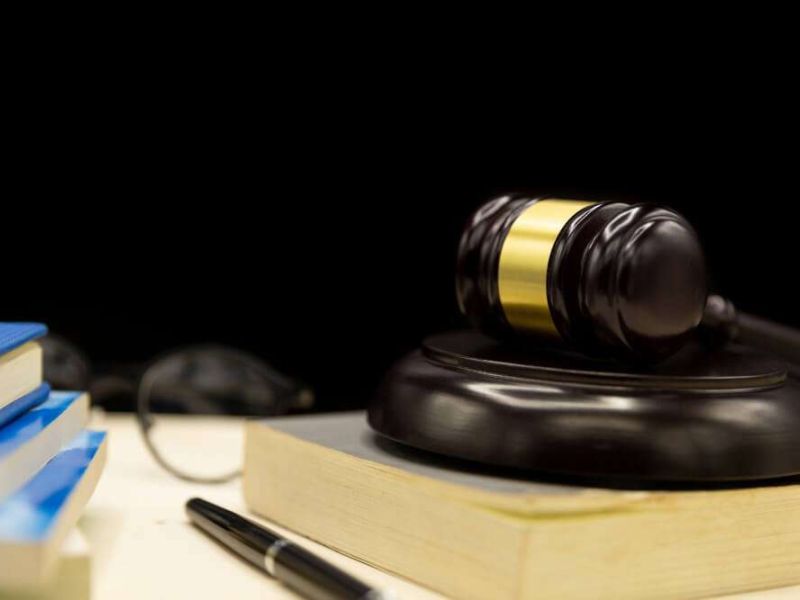 Gavel and books on desk, symbolizing law and justice in a courtroom or legal office setting.