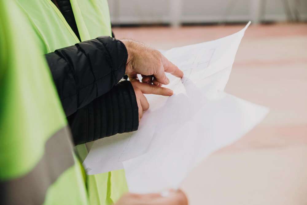 Construction workers reviewing blueprints on site.