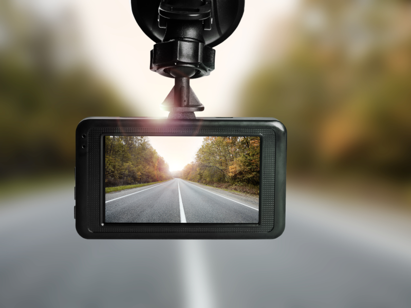 Close-up of a dashboard camera recording a road view through a car windshield.