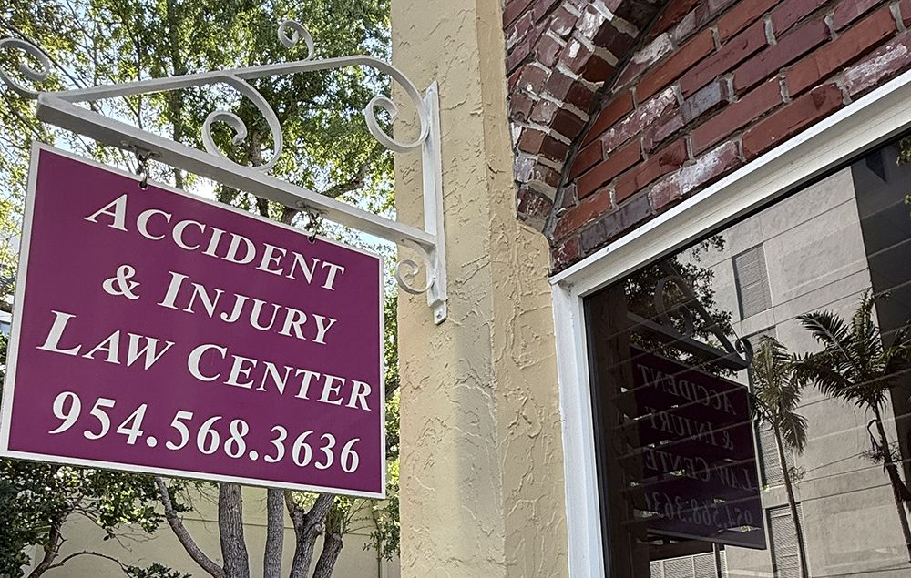 Sign for Accident & Injury Law Center with contact number 954.568.3636, on a building exterior.