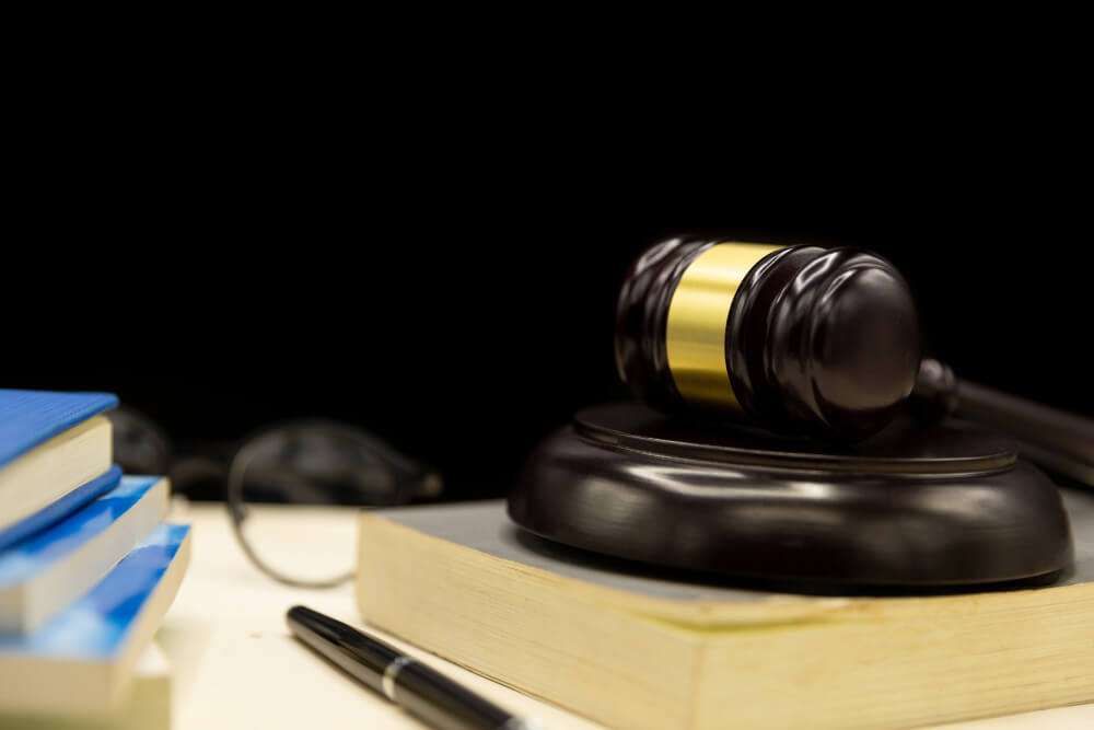 Gavel and books on desk, symbolizing law and justice in a courtroom or legal office setting.