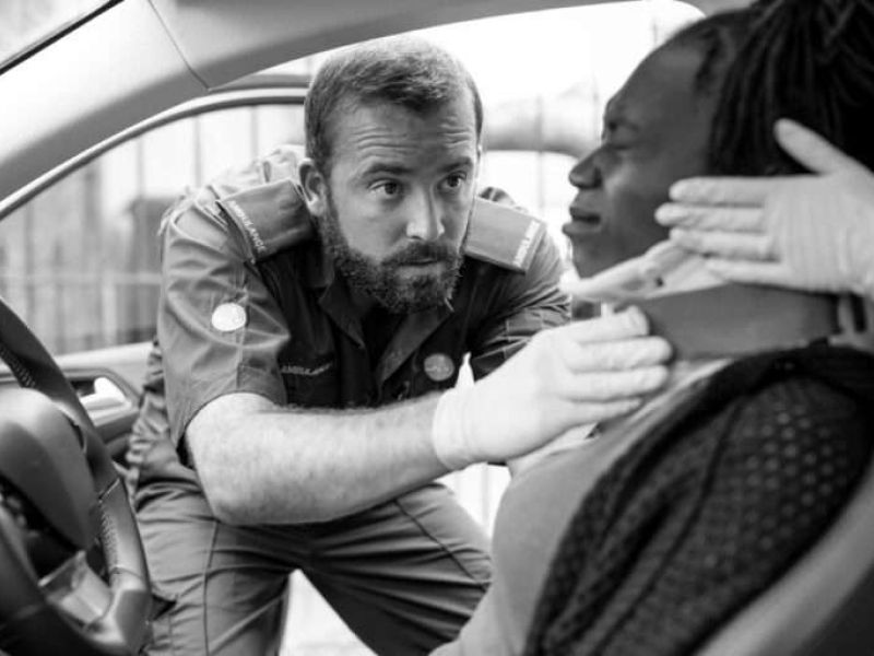 Paramedic assists car accident victim with neck brace for safety and care.