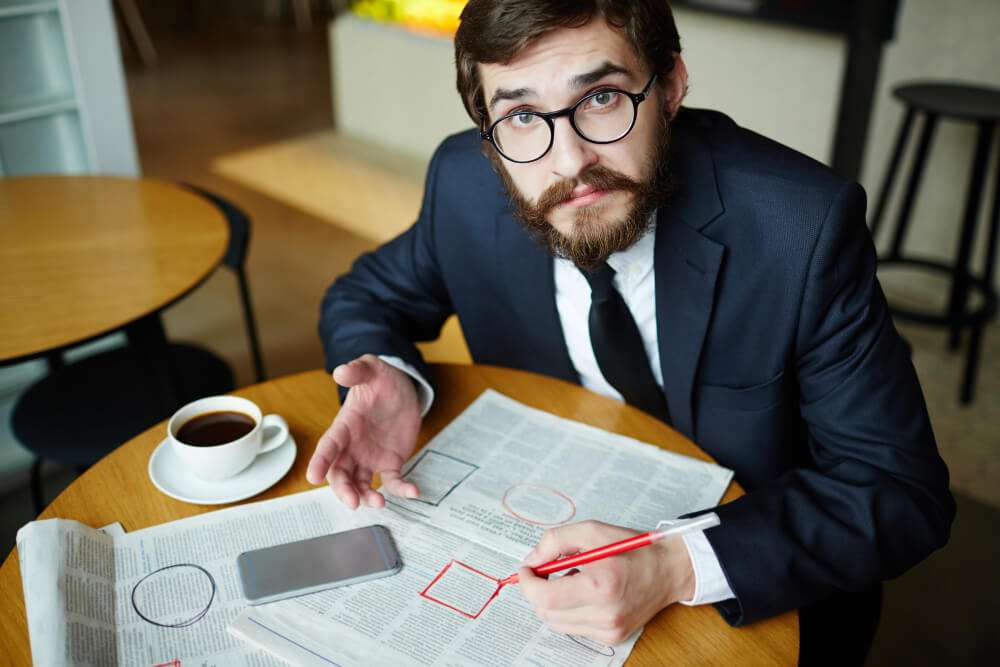 Man in suit reading newspaper at cafe table