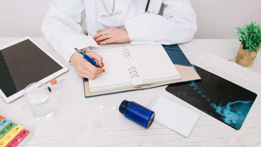 Doctor writing notes at desk with tablet