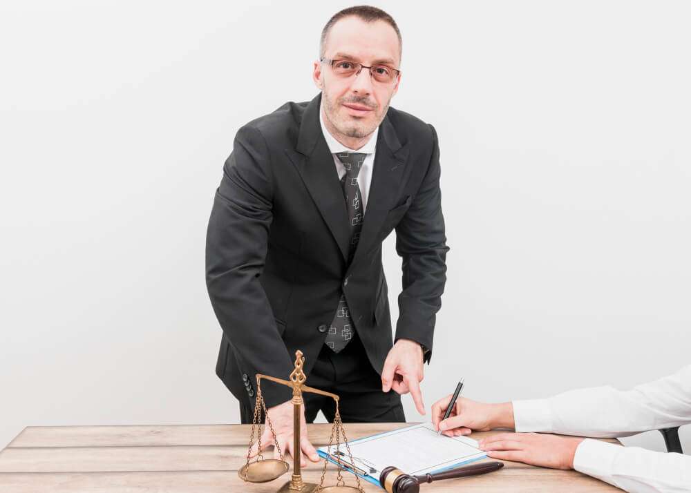 Male lawyer pointing to document with scales and gavel on desk
