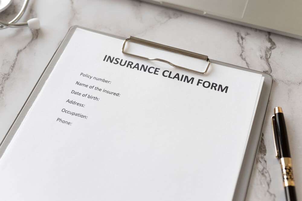 Insurance claim form on a clipboard with a pen on a marble desk