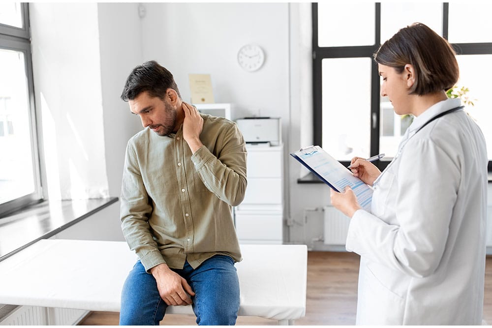 Male patient with neck pain consulting a doctor in a clinic.