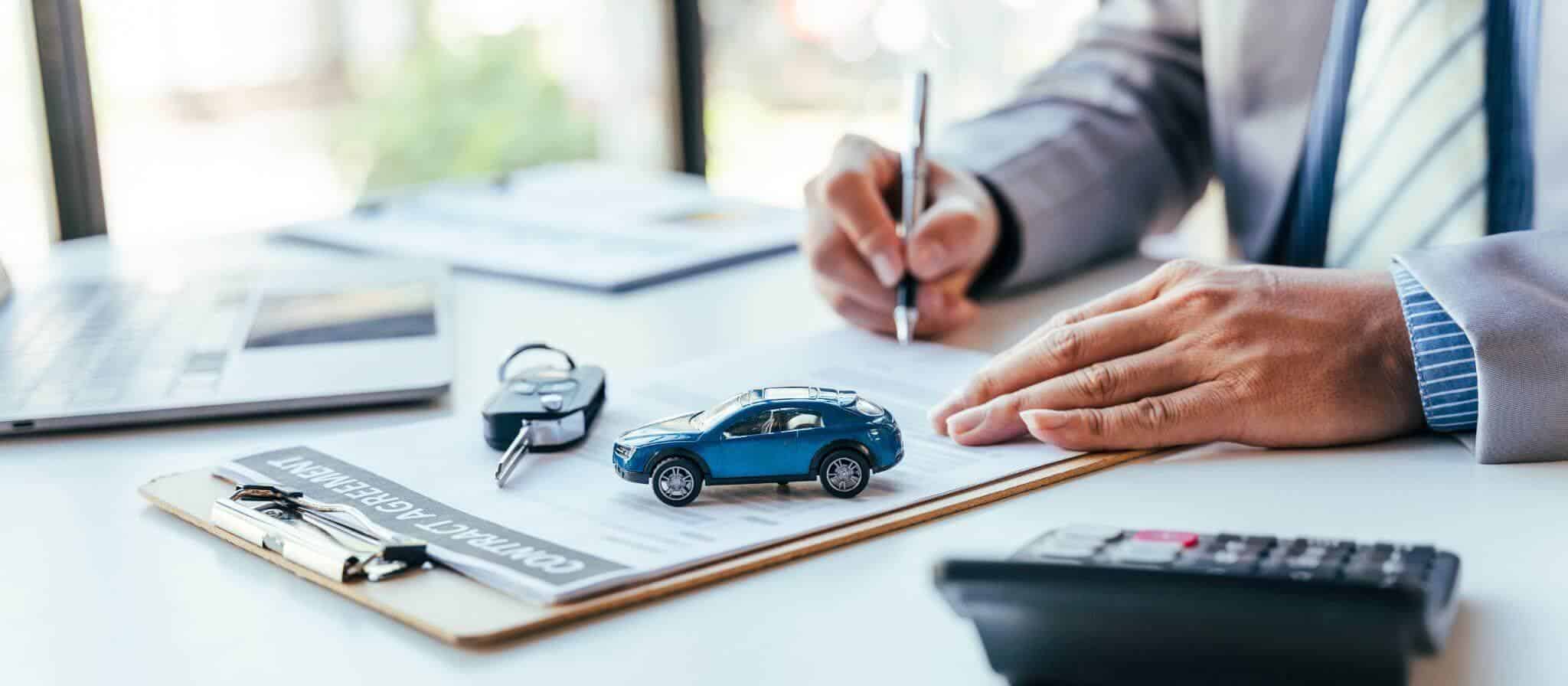 a person signing a car purchase form on a desk