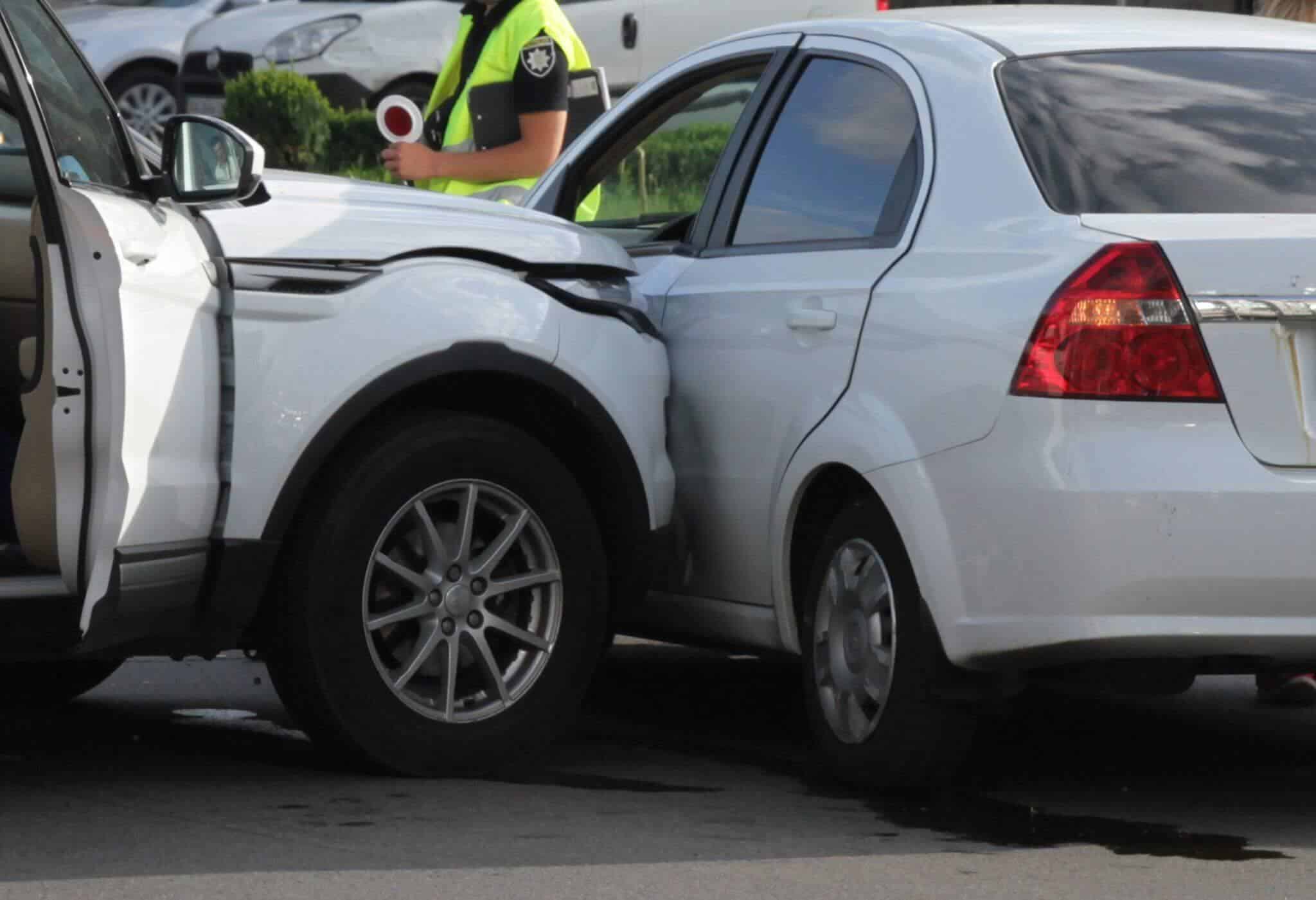 a police officer standing next to a white truck that crashed into a white car