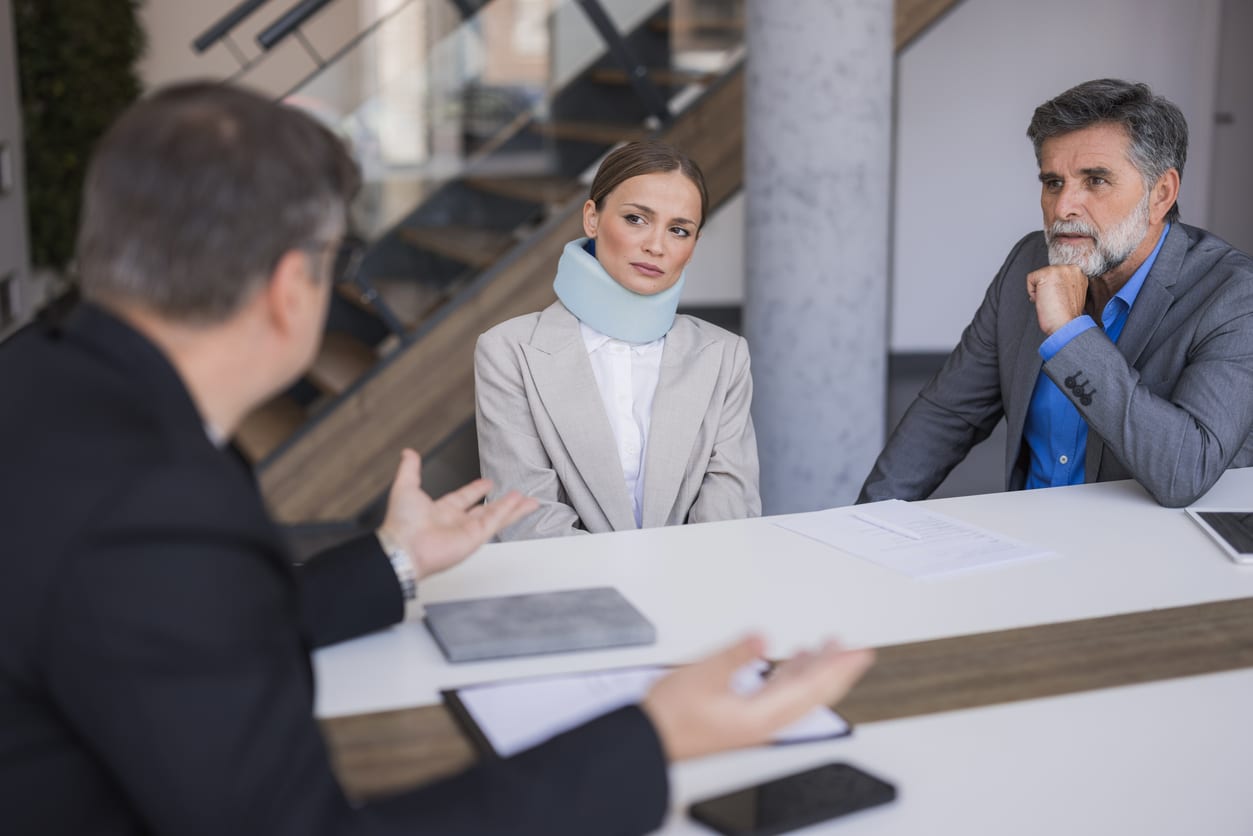 Woman in neck brace meeting lawyer about personal injury lawsuit